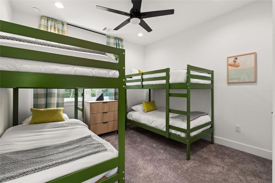 This bedroom features a modern ceiling fan, soft carpeting.