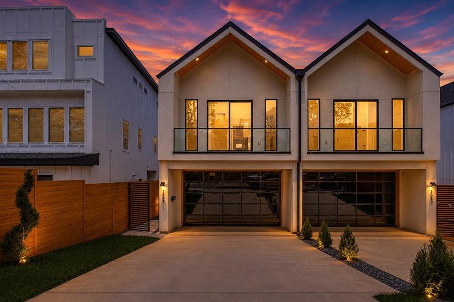 Contemporary duplex featuring a stucco and siding exterior, prominent gabled roofs, and an attached two-car garage with frosted glass panel doors