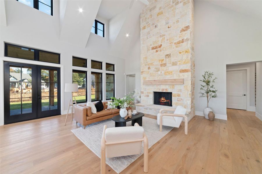 Stunning living room with soaring ceilings, expansive windows, grand stone fireplace, and abundant natural light.