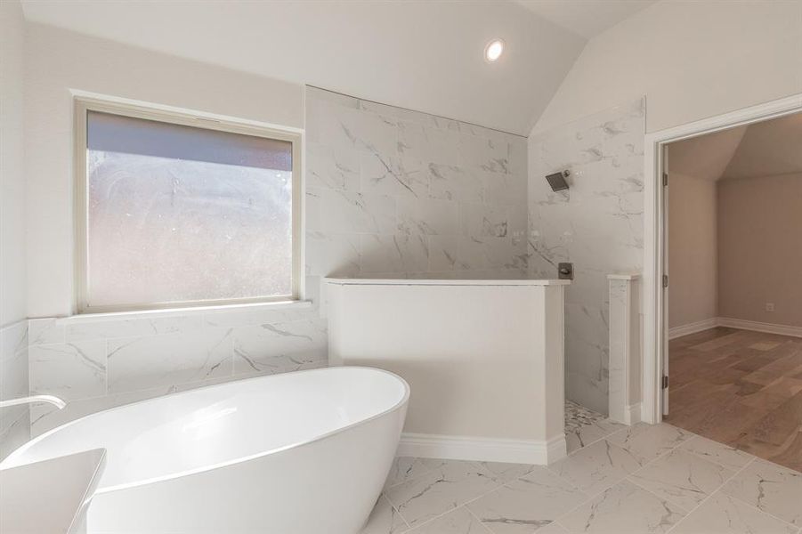 Bathroom featuring hardwood / wood-style floors, plus walk in shower, and vaulted ceiling