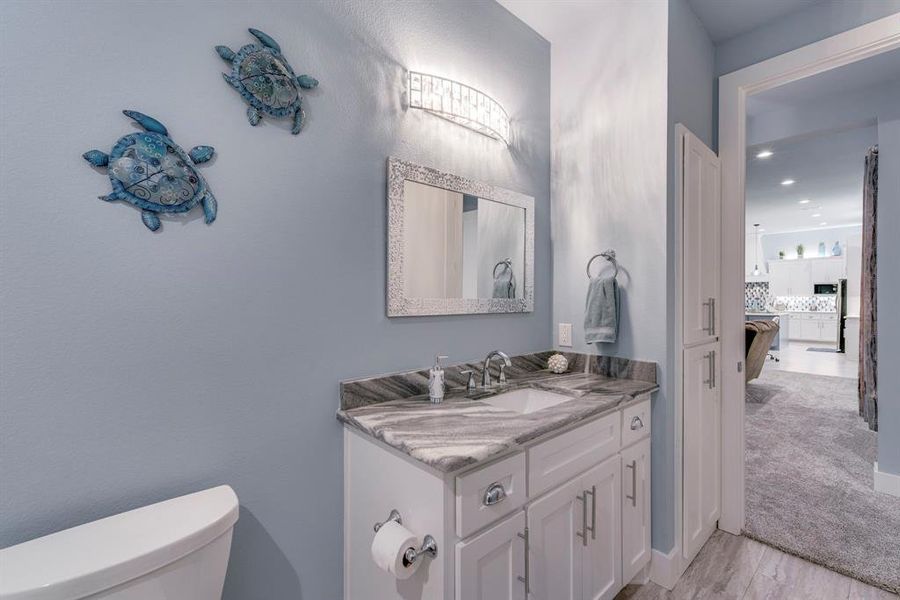 Bathroom with vanity, light wood finished floors, decorative backsplash, and recessed lighting