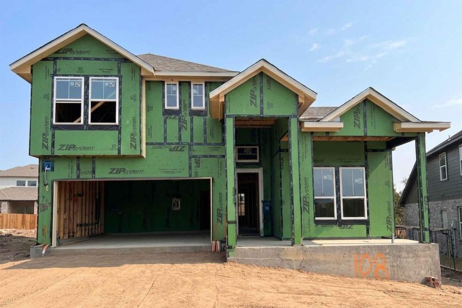Property under construction featuring an attached garage, driveway, and a shingled roof