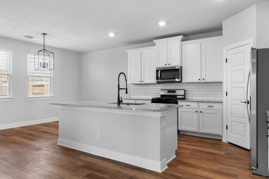 Kitchen featuring light stone counters, backsplash, a center island with sink, stainless steel appliances, and recessed lighting
