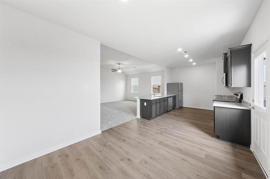 Kitchen featuring a peninsula, open floor plan, recessed lighting, light wood-style flooring, and ceiling fan