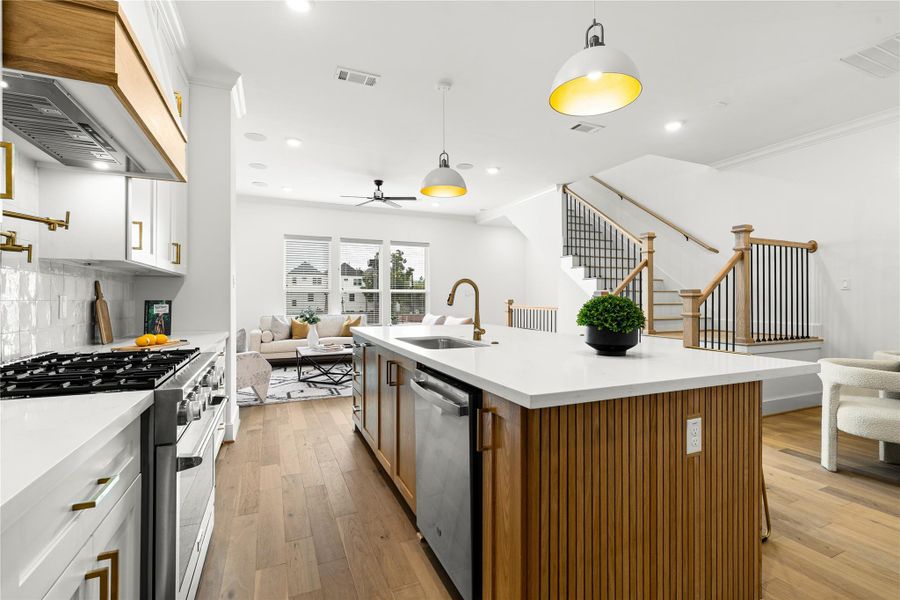 A large island with a built-in sink accented by premium Moen fixtures, sleek stainless steel appliances, and a seamless flow into the living area - perfect for both everyday living and entertaining.