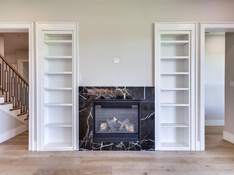 Detailed view of baseboards, built in features, wood finished floors, and a fireplace