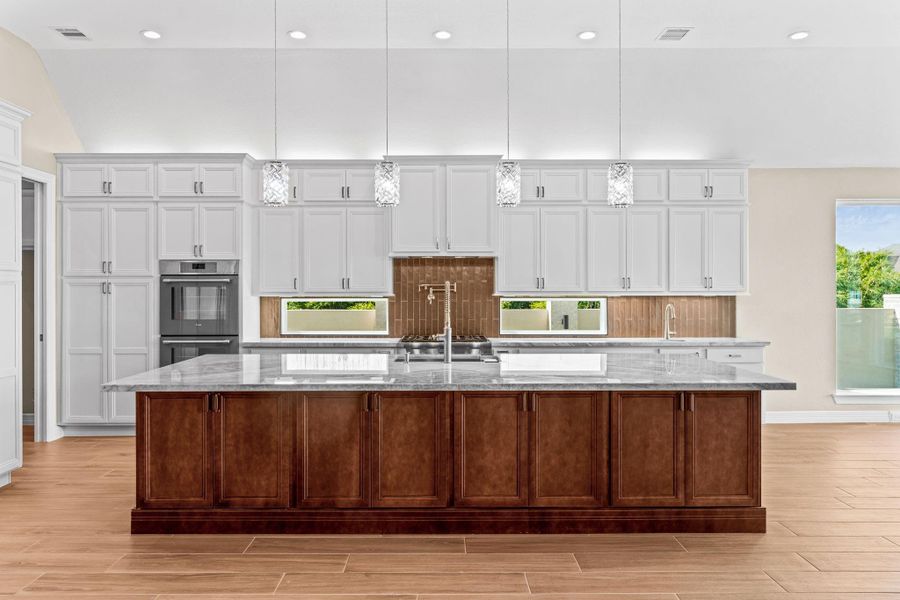 Center-island view showcasing expansive counter space, contrasting cabinetry, and designer lighting.
