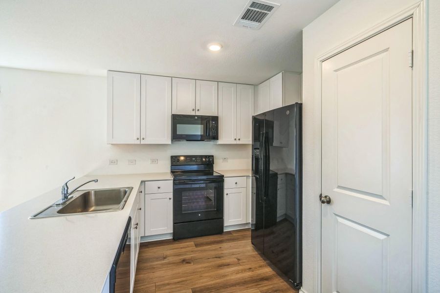A well-appointed kitchen features black appliances set against crisp white cabinetry and light countertops. A well-appointed kitchen features black appliances set against crisp white cabinetry and light countertops.