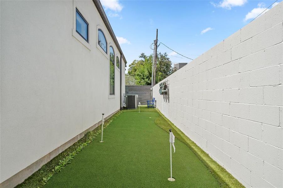 This side yard features a custom putting green which wraps around two sides of the house and offers a perfect space for practicing your golf skills in a private and serene setting. The artificial turf is bordered by the home’s exterior, creating a low-maintenance, functional area for leisure and recreation.