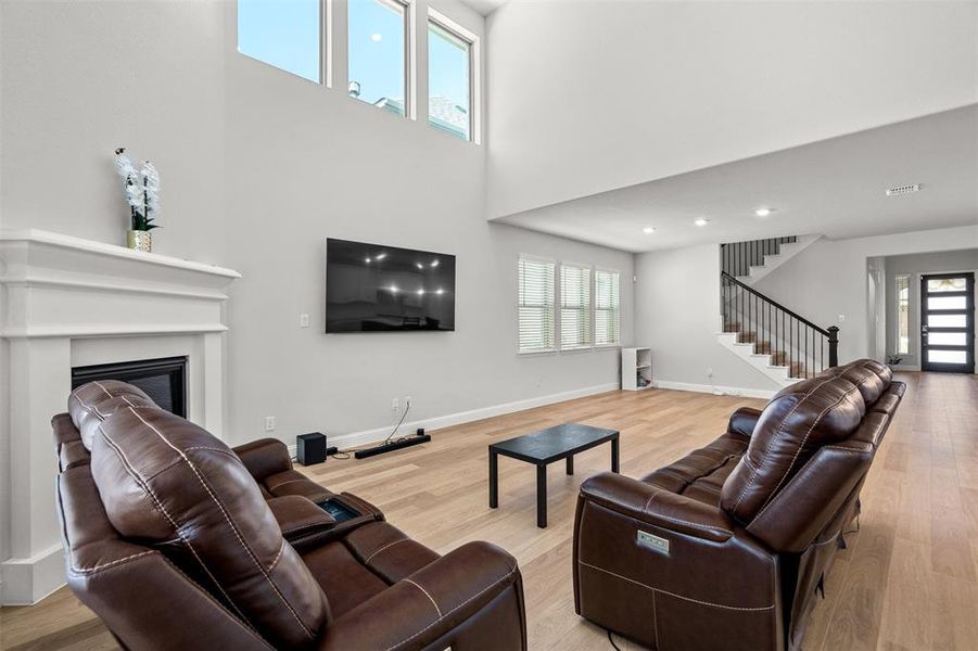 Living room featuring a high ceiling, light hardwood / wood-style flooring, and a wealth of natural light