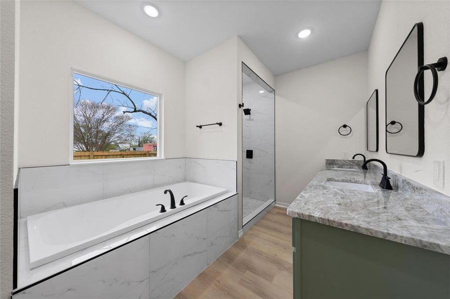 Full bathroom with a bath, double vanity, light wood-style floors, a marble finish shower, and recessed lighting