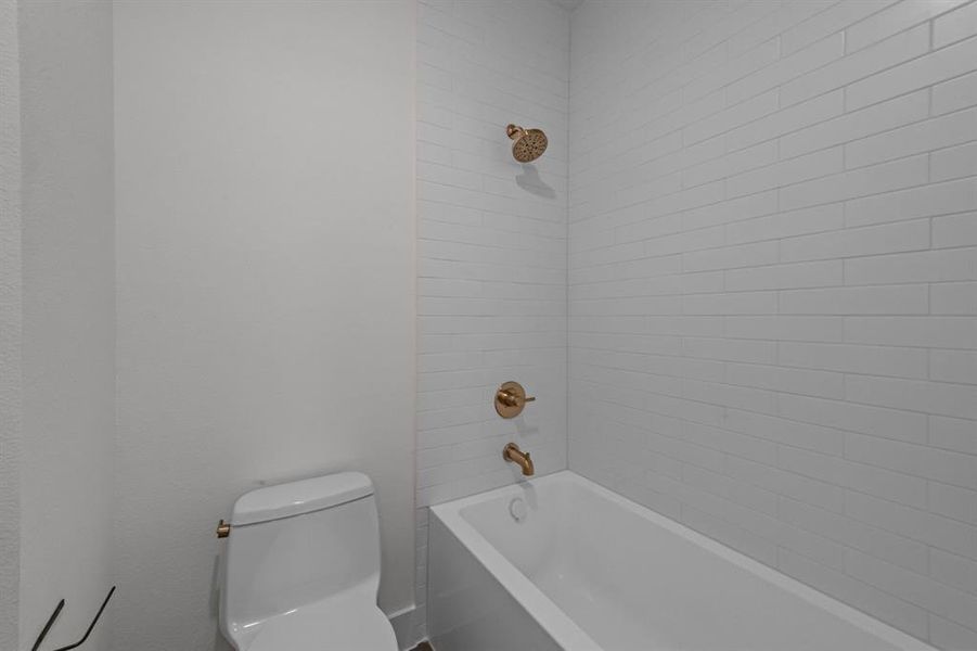 Bathroom with tiled shower / bath combo and toilet