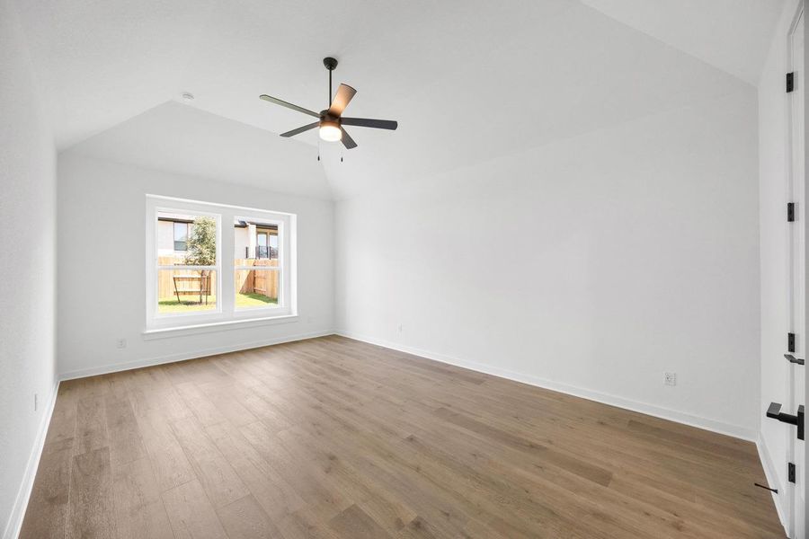 Empty room featuring light wood-type flooring, lofted ceiling, and a ceiling fan Empty room featuring light wood-type flooring, lofted ceiling, and a ceiling fan