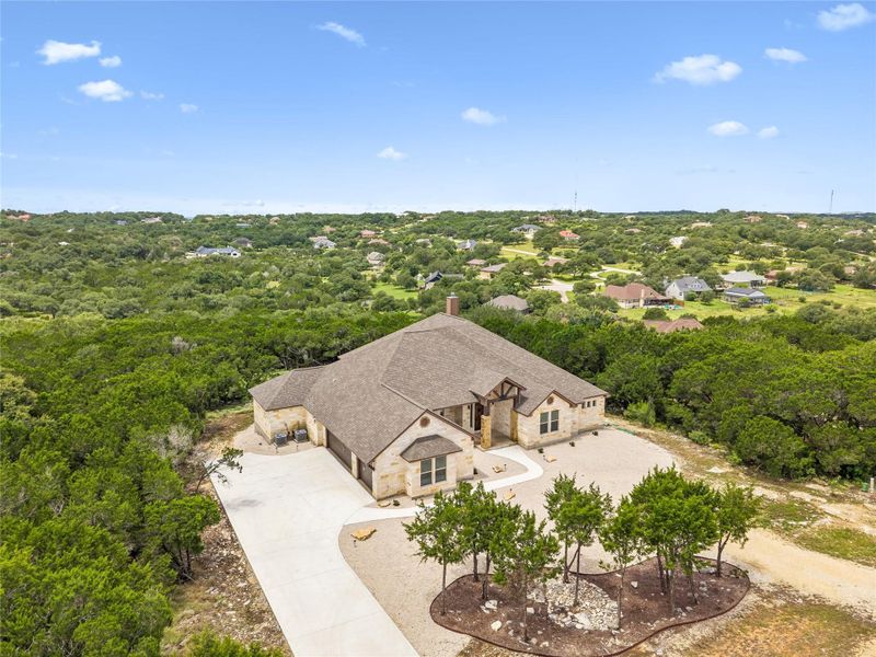 An aerial perspective reveals a handsome stone and stucco residence nestled amidst verdant natural landscaping.