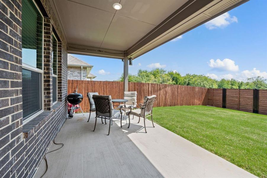 Covered patio with plenty of room for seating or grilling, perfect for relaxing or entertaining outdoors.