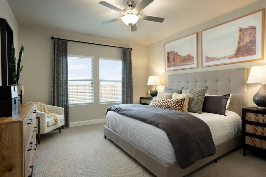 Bedroom featuring neutral carpeting, a ceiling fan, and two windows with blinds and curtains