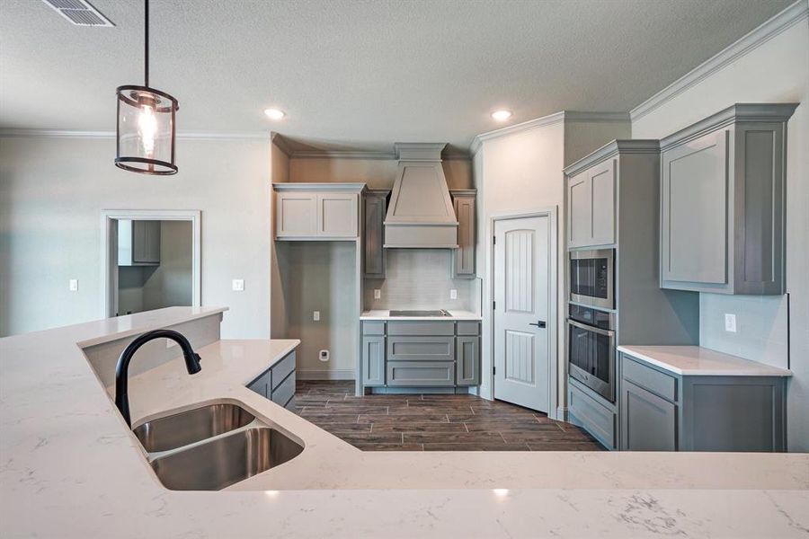 Kitchen featuring pendant lighting, sink, dark hardwood / wood-style floors, custom range hood, and appliances with stainless steel finishes