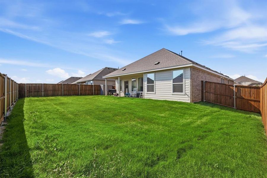 Expansive backyard featuring a manicured lawn, full wood privacy fencing, and a covered patio area with a concrete slab Expansive backyard featuring a manicured lawn, full wood privacy fencing, and a covered patio area with a concrete slab