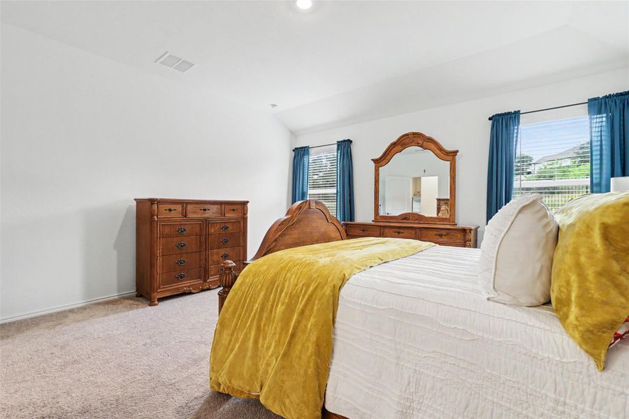 Spacious room featuring vaulted ceilings, light neutral wall paint, and light-tone carpeting