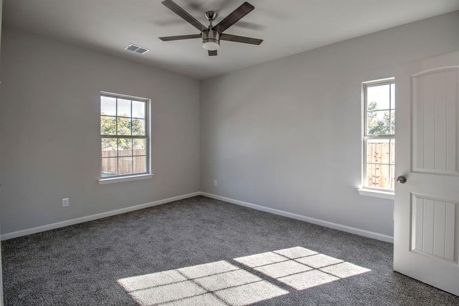 Unfurnished room with ceiling fan and dark carpet