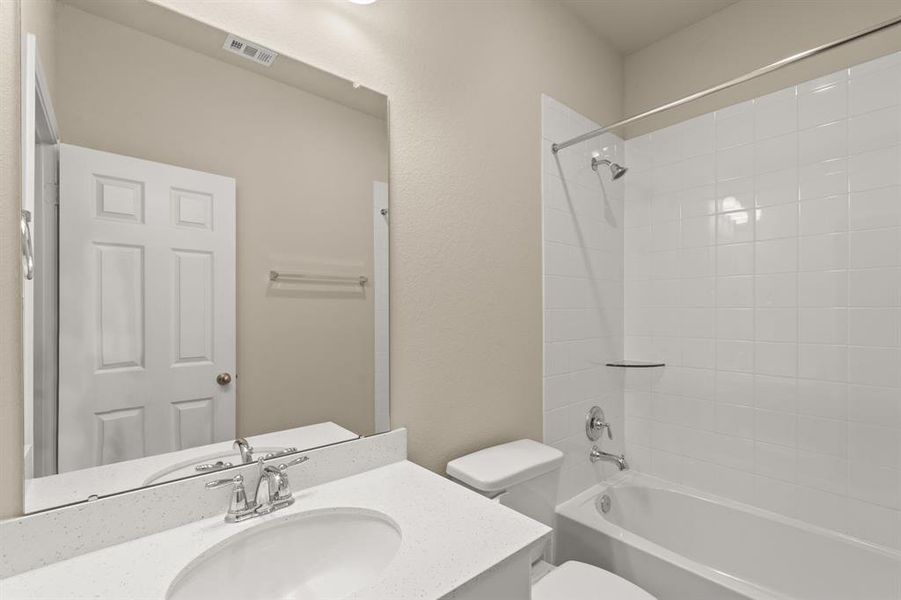 The secondary bath features tile flooring, white cabinetry and light countertops and a shower/tub combo. Perfect for accommodating any visiting family and friends.