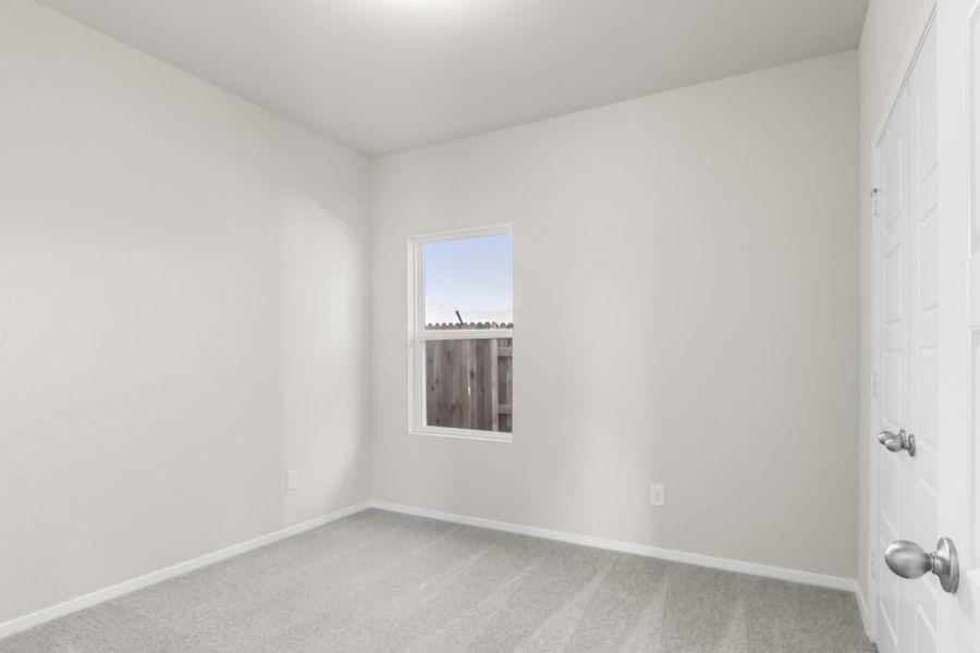 Image of a bedroom with cream walls. tan carpeting, white trim and a window