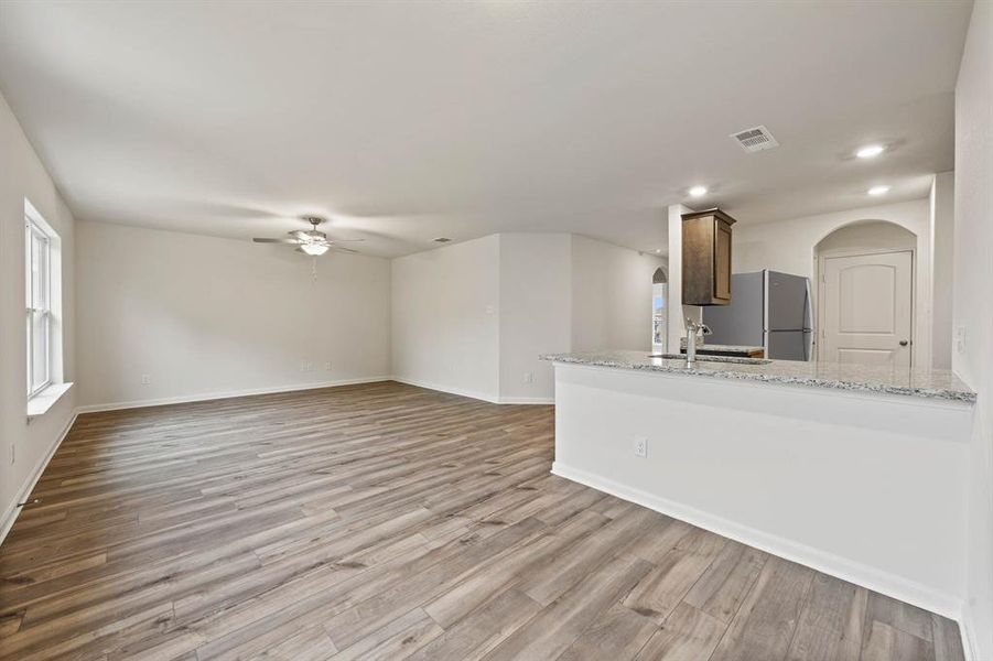 Unfurnished living room with baseboards, ceiling fan, recessed lighting, wood finished floors, and a sink