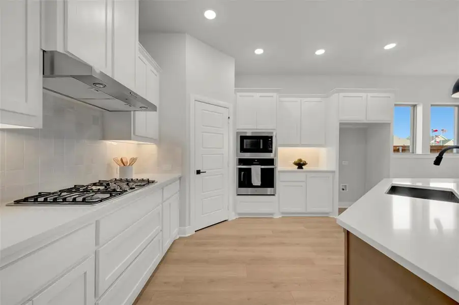 Kitchen featuring white cabinets, stainless steel appliances, recessed lighting, light wood-style floors, and tasteful backsplash