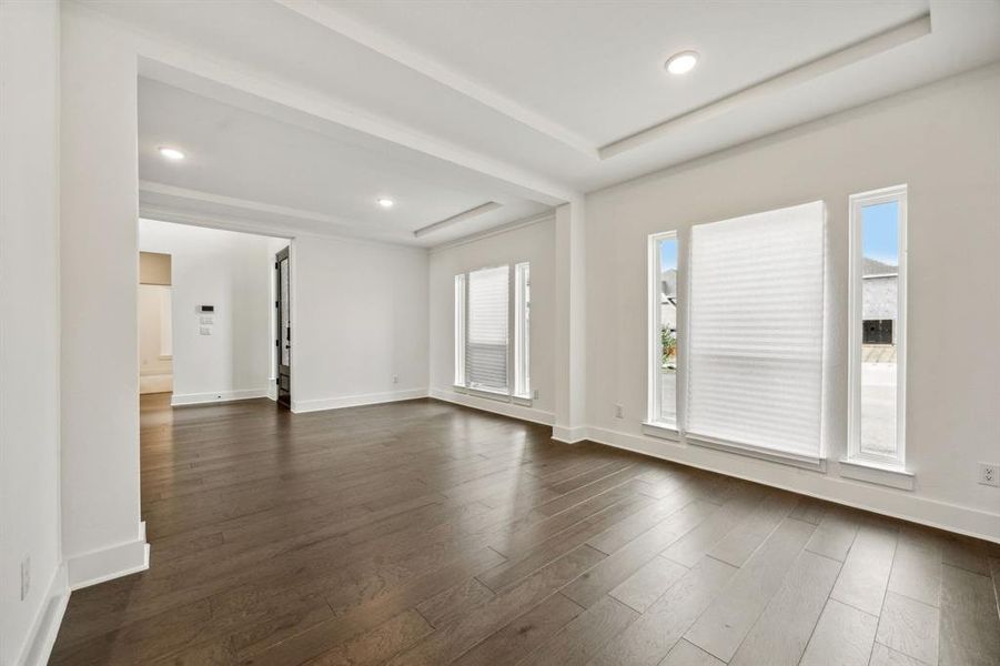 Unfurnished living room featuring a tray ceiling and dark hardwood / wood-style floors