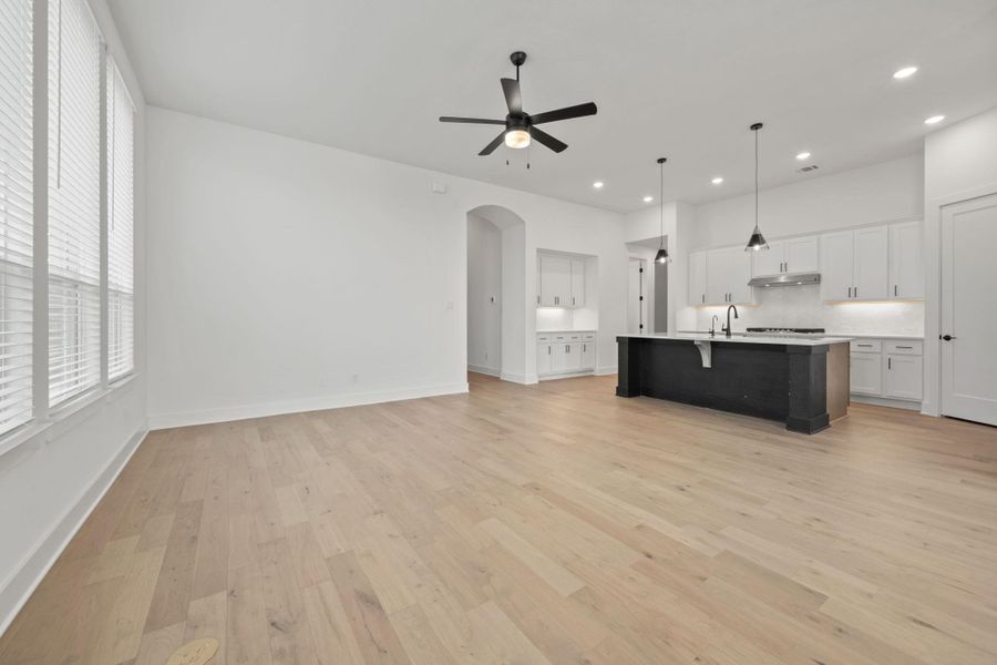 Kitchen featuring white cabinetry, open floor plan, decorative backsplash, arched walkways, and pendant lighting
