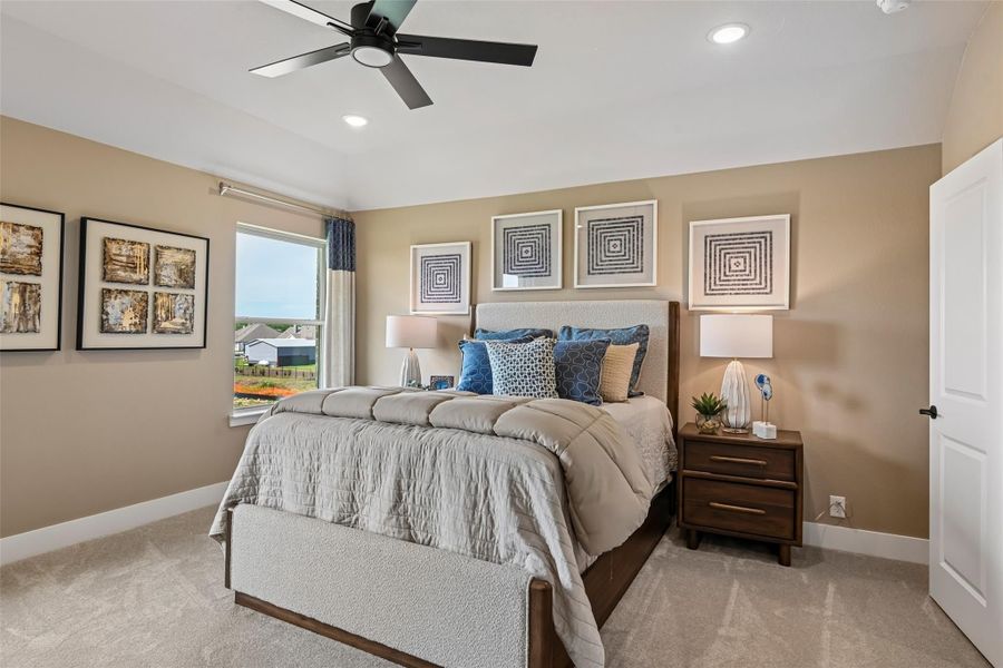 Bedroom with king bed, ceiling fan, carpet flooring, and large window with natural light Bedroom with king bed, ceiling fan, carpet flooring, and large window with natural light