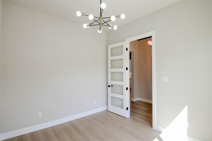 Empty room with light wood-style flooring and a chandelier Empty room with light wood-style flooring and a chandelier