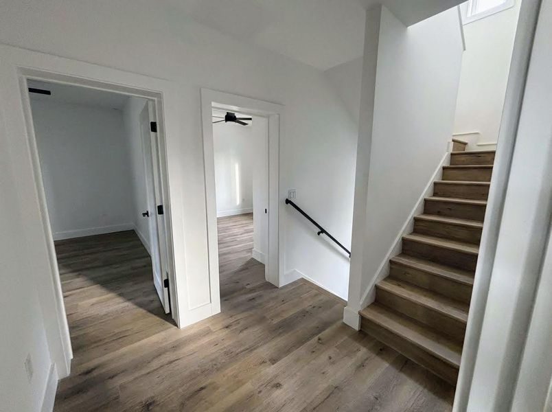 Stairway featuring wood finished floors and a ceiling fan