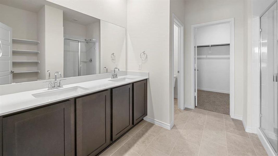 Bathroom with a spacious closet, a stall shower, double vanity, and light tile patterned flooring