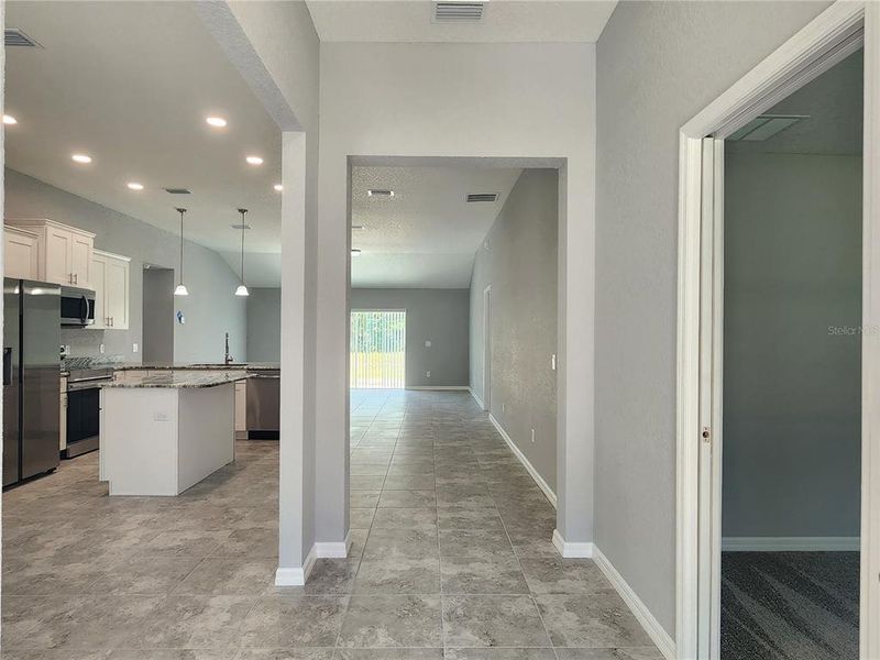 Foyer with 4th bedroom with pocketing door to the right and kitchen and dining to the left