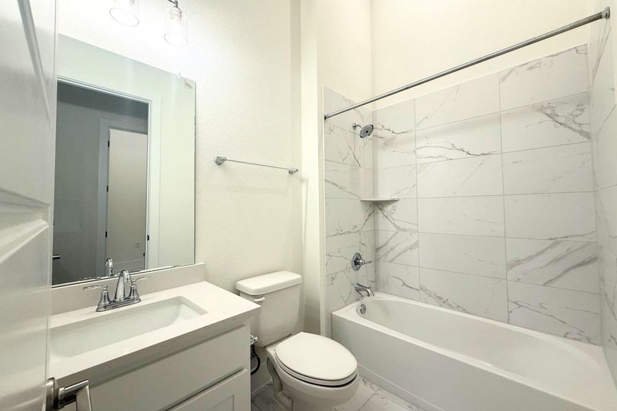 Bathroom featuring a white vanity with an integrated sink, polished chrome faucet, and quartz-finish countertop