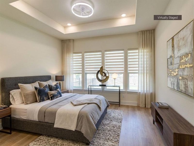 Room featuring wood-finish flooring, a tray ceiling with recessed lighting, and a modern ceiling fan