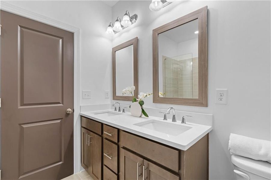 Primary Bathroom with framed mirrors, quartz countertops & Delta Plumbing fixtures *Images shown are from a decorated model of the same floor plan. Design selections and color packages will vary by home.*