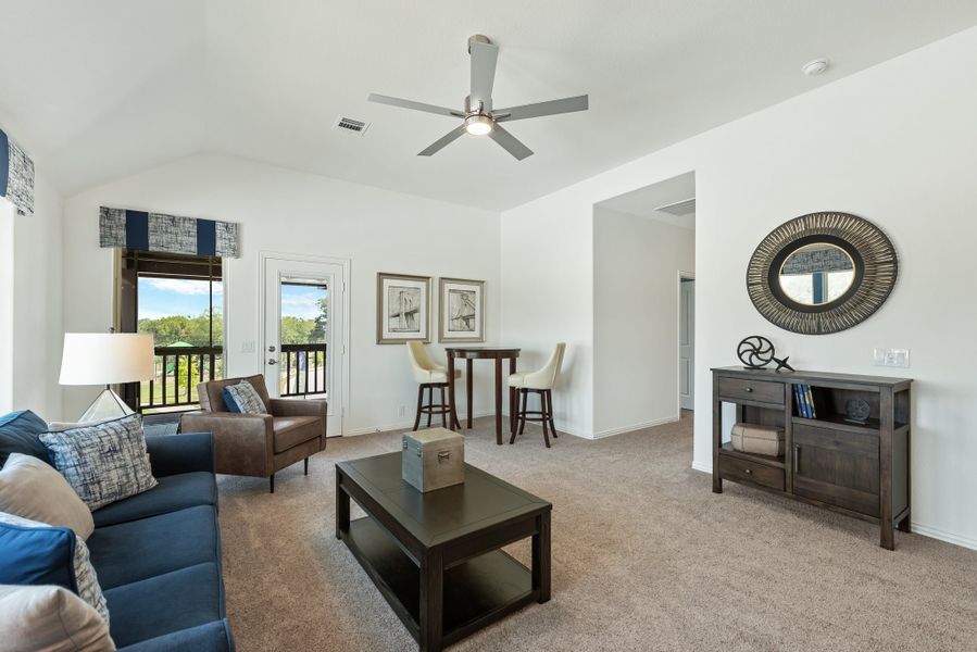 Living room with vaulted ceiling, ceiling fan, blue sofa, and carpet flooring with balcony access