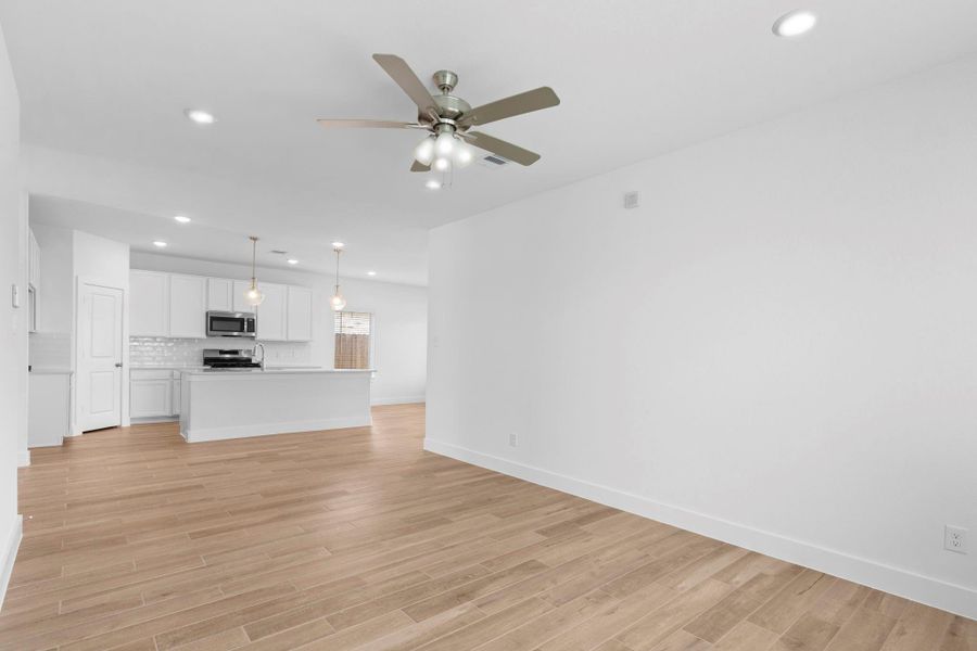 Large, versatile living space with wood-look tile flooring and a ceiling fan, offering flexible furniture placement options.  Wonderful open concept!