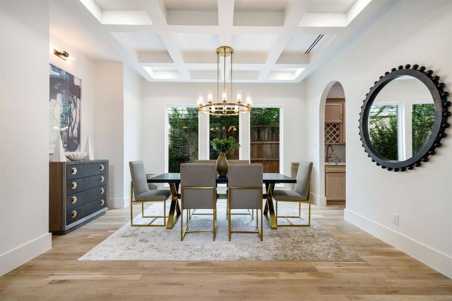 Dining area featuring a coffered ceiling, wood-finish flooring, and a contemporary chandelier Dining area featuring a coffered ceiling, wood-finish flooring, and a contemporary chandelier