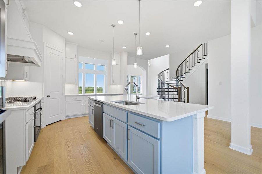 Kitchen featuring a light blue island with a built-in sink and stainless steel dishwasher