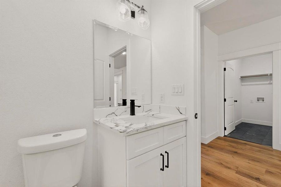 Half bathroom featuring vanity and light wood finished floors Half bathroom featuring vanity and light wood finished floors