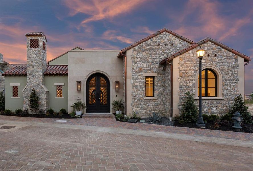 View of front facade with french doors, stone siding, a tiled roof, stucco siding, and a chimney View of front facade with french doors, stone siding, a tiled roof, stucco siding, and a chimney