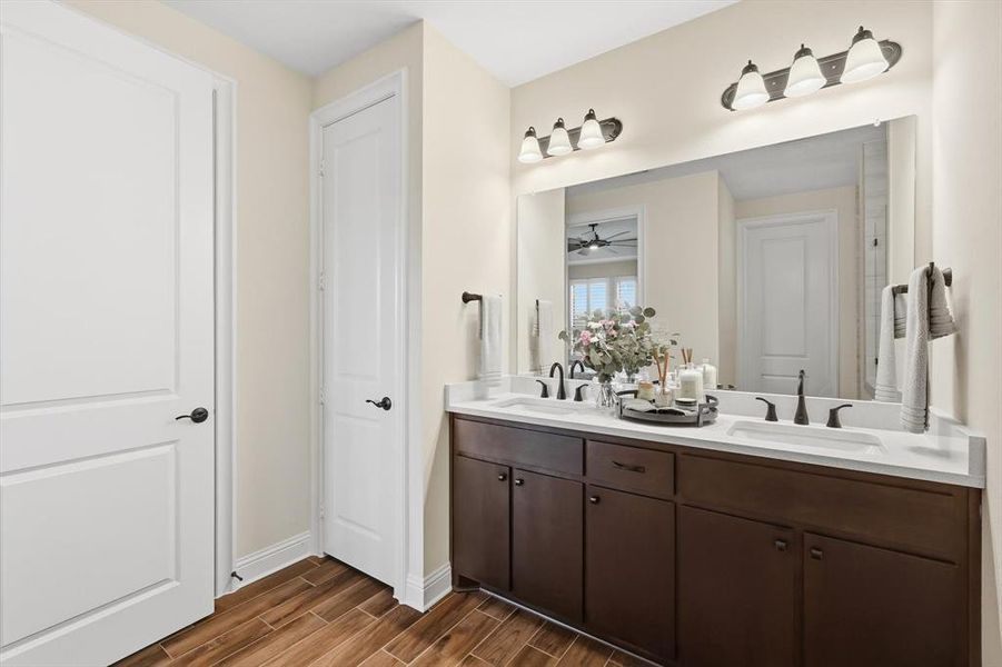 Bathroom with double vanity, wood tiled floors, and a ceiling fan