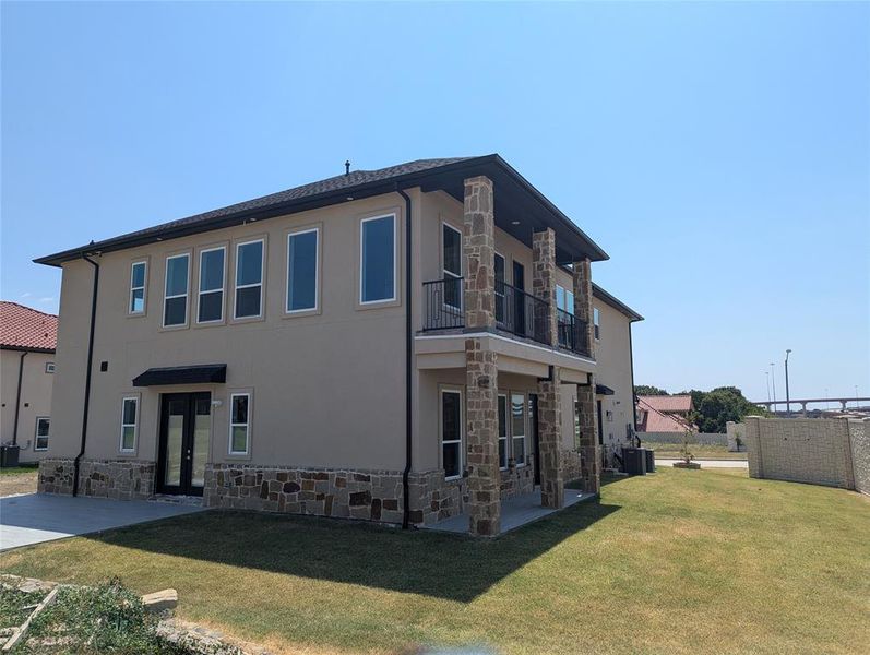 Rear view of house featuring a balcony, a yard, central AC, and a patio