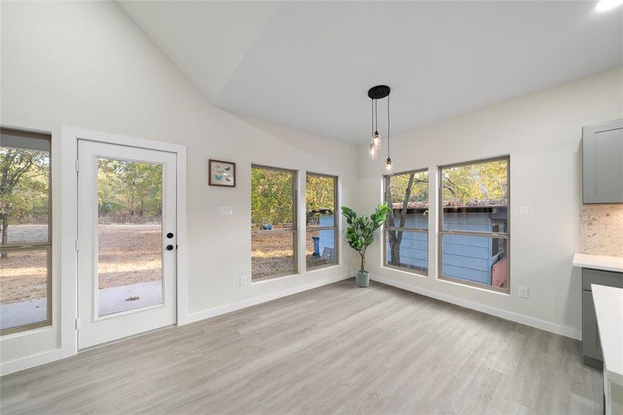 Unfurnished dining area featuring light hardwood / wood-style flooring, vaulted ceiling, and a wealth of natural light