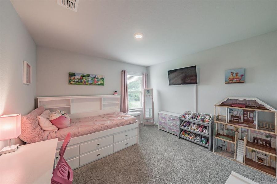 Spacious room featuring light gray walls, textured carpeting, an integrated ceiling light, and a window with blinds
