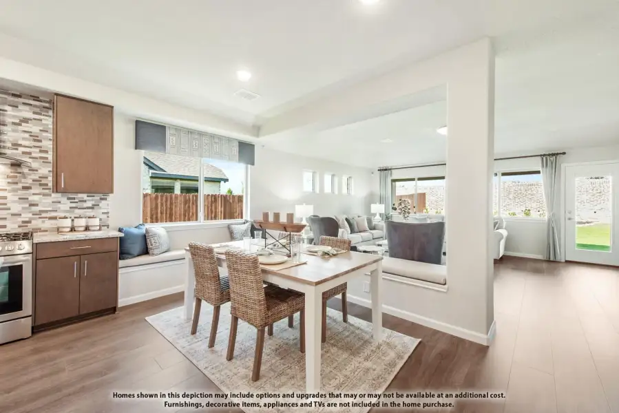 Open-concept dining area with kitchen nook, wicker chairs, wood floors, and living room visible beyond partial wall