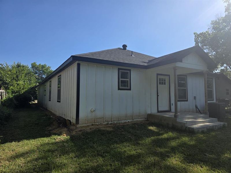 Back of house with board and batten siding, a yard, and roof with shingles Back of house with board and batten siding, a yard, and roof with shingles